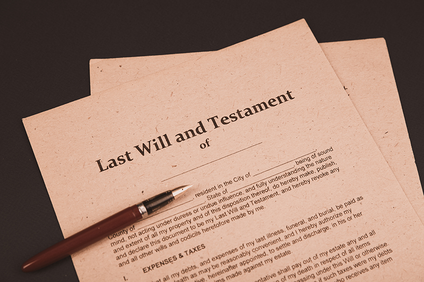 Cozakos and Centeno : A pen rests on a "last will and testament" document against a black background.